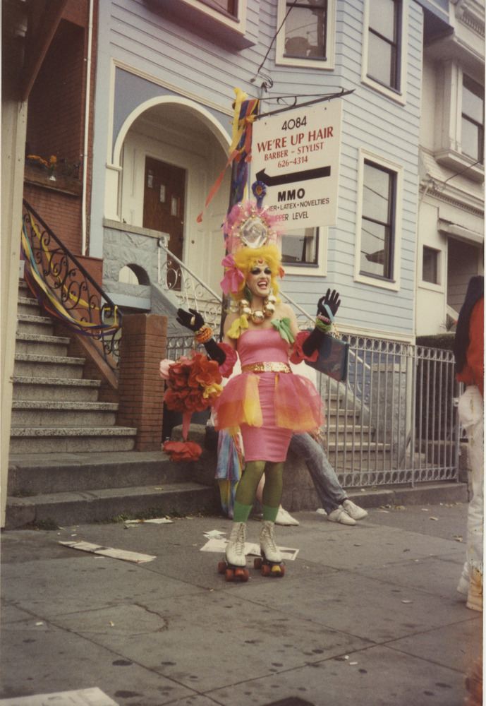 Download the full-sized image of Photograph of Person on Street in Drag with Pink Dress and Colorful Accessories