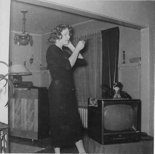 Download the full-sized image of Unknown femme looking at hand mirror in living room